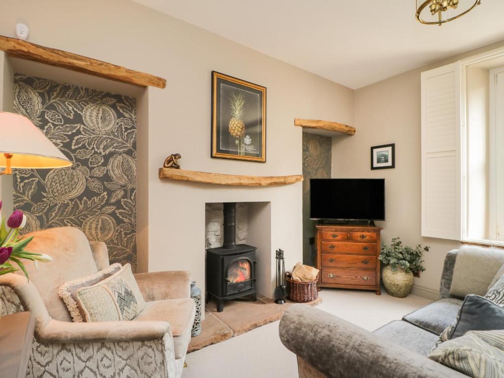 a living room with a fireplace and a tv at Hideaway Cottage in Penrith