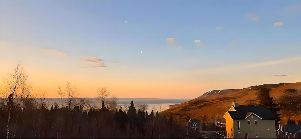 a house sitting on the side of a hill next to the ocean at Bleuzen chalet entier in Petite-Rivière-Saint-François