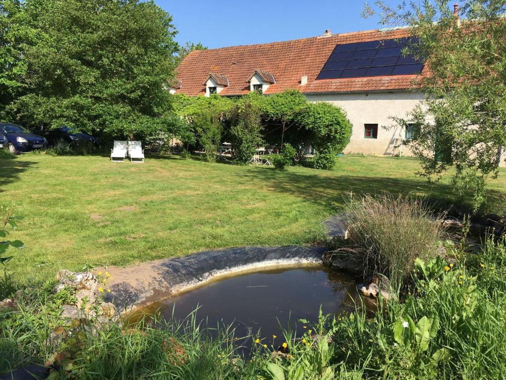 uno stagno in un cortile con una casa con pannelli solari di Charmant gîte rénové en Berry avec grand terrain, cheminée, et proximité UNESCO et thermes - FR-1-591-212 a Mauvières
