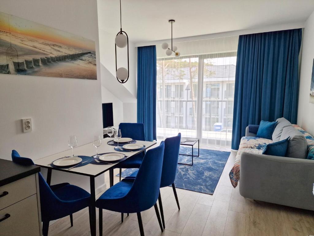 a dining room and living room with a table and chairs at Rezydencja Niechorze Lazurowy A326 z dostępem do Basenu in Niechorze