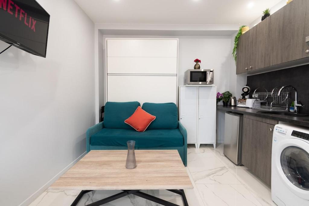 a living room with a blue chair with a red pillow at Appartement cosy A Paris RER B in Gentilly