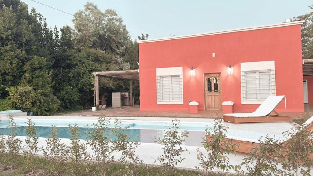 a red house with a pool in front of it at La Colorada Dolores in Dolores