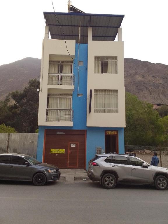 two cars parked in front of a blue and white building at Hospedaje TUTUMEME in Churín