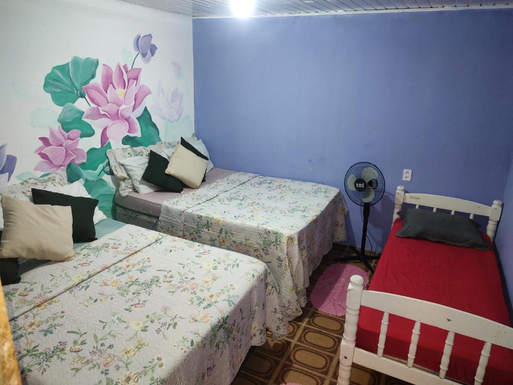 a bedroom with two beds and a wall with flowers at Pousada Villa Da Música Beira Mar Lótus Pontal Centro in Paraty