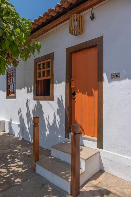 a house with an orange door and stairs outside at Conforto no Centro de Pirenópolis in Pirenópolis