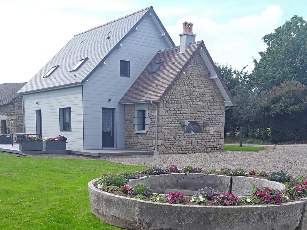 a house with a flower bed in front of it at Maison rénovée avec jardin, terrasse et recharge électrique gratuite près de la Suisse Normande - FR-1-497-178 in Sainte-Opportune