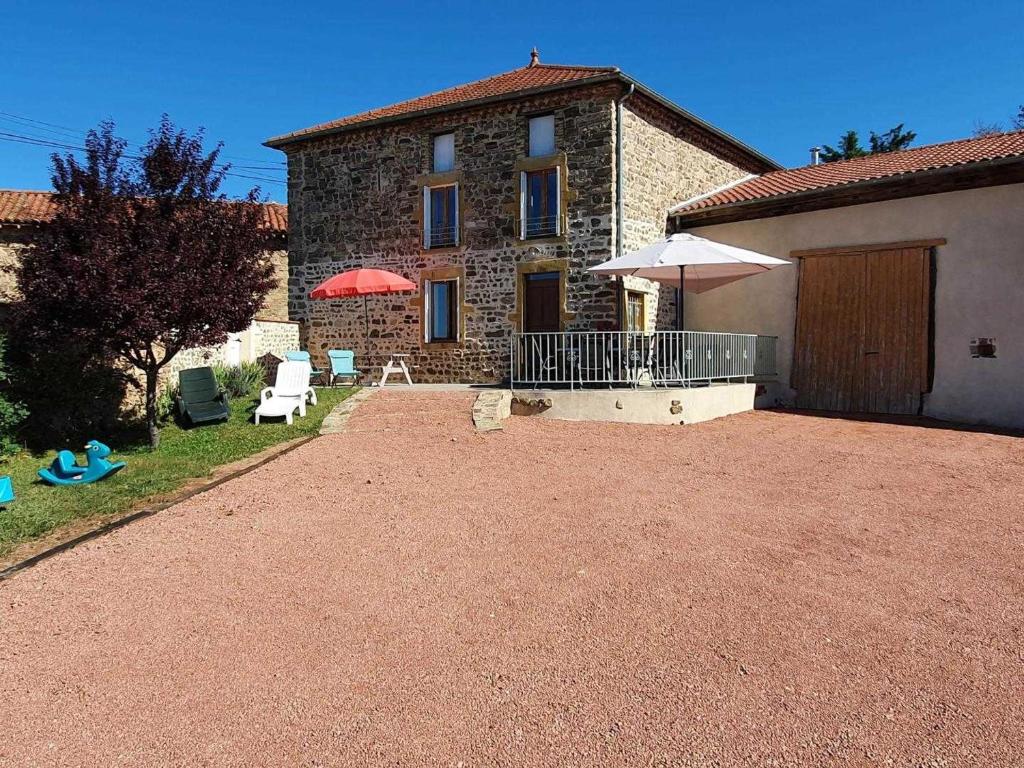 una casa con un patio, un ombrellone e delle sedie di Grande maison de campagne avec cheminée, jardin et Wifi - FR-1-496-273 a Saint-Paul-de-Vézelin