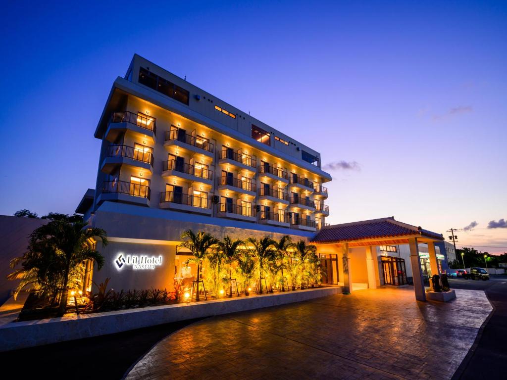 a hotel with palm trees in front of a building at Lit Hotel NAKIJIN in Nakijin