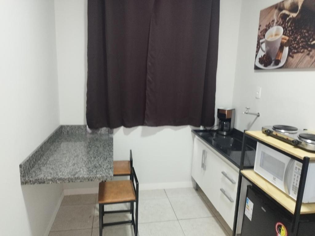 a small kitchen with a counter and a microwave at Apartamento loft in Poços de Caldas