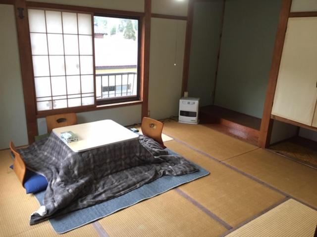 a room with a bed with a blanket on the floor at わくわく自然体験の宿ゲストハウス山楽 in Itoigawa