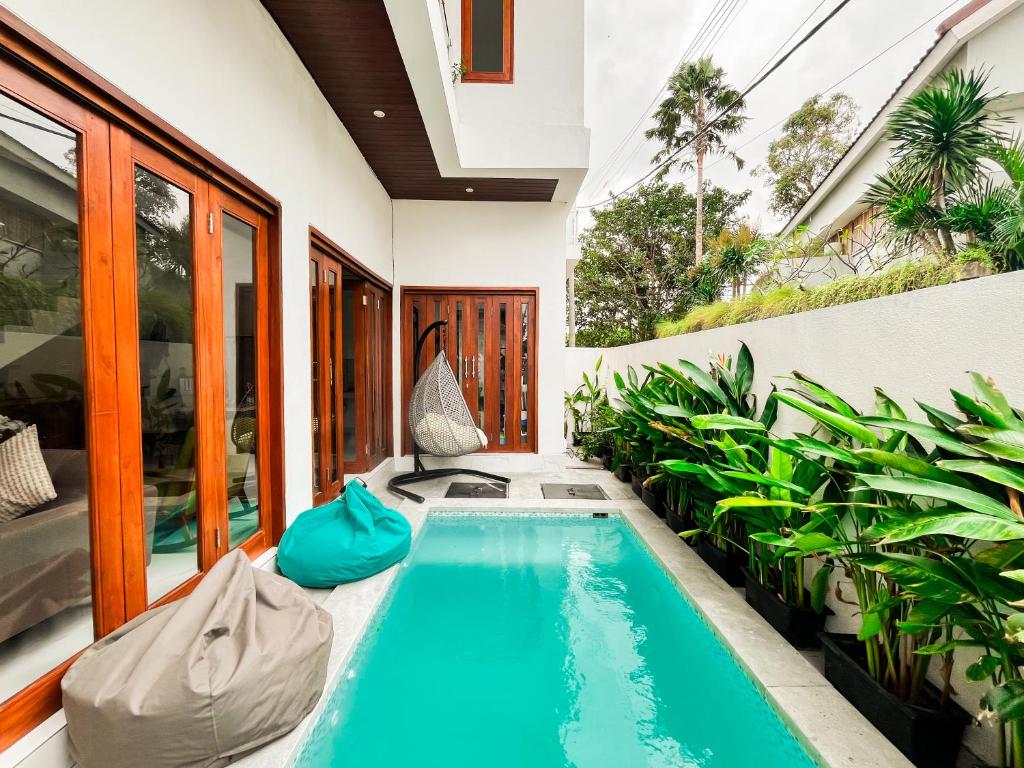 an indoor swimming pool in a house with plants at KAUH House Canggu in Tumbak Bayuh
