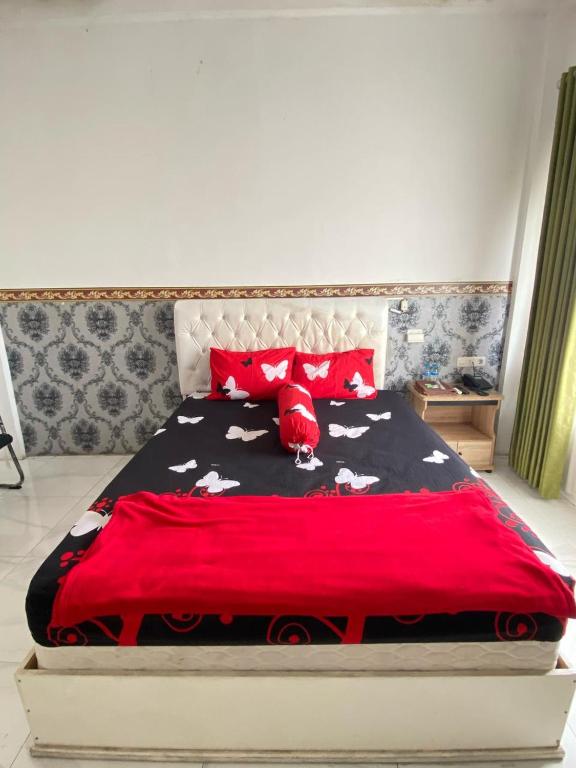 a bedroom with a bed with a red comforter with cows on it at Kasdin Hotel Pati in Pati