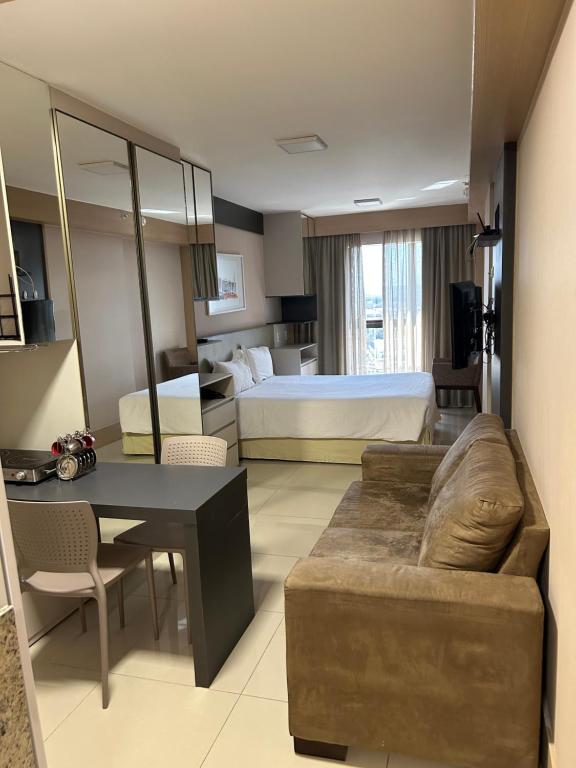 a large hotel room with a bed and a couch at Flat em Cullinan, 5 estrelas com vista incrível e incrível área de lazer com piscinas, brinquedoteca, academia, no coração de Brasília in Brasilia
