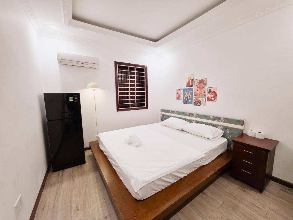 a bedroom with a white bed and a black refrigerator at 202 부이비엔 도보 10분 , 아늑한 주택 in Ho Chi Minh City