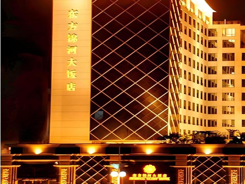 wysoki budynek z znakiem przed nim w obiekcie Oriental Glory Hotel w mieście Dongguan