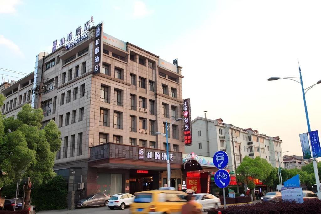a yellow taxi driving down a city street with buildings at Yitel Shanghai Hongqiao Railway Station National Convention and Exhibition Center in Fangjiayao