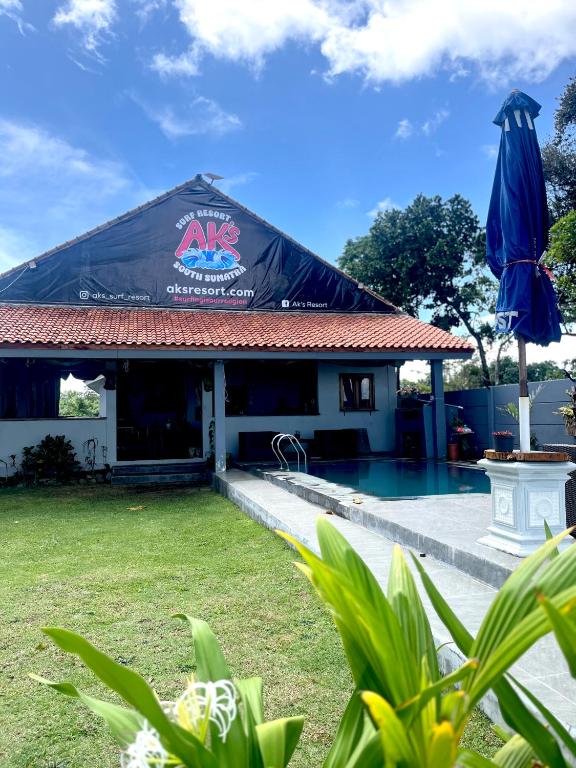 a building with a black roof next to a swimming pool at AK's Surf Resort in Wainapal