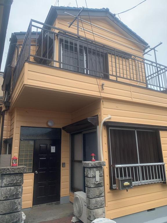 ein Haus mit einem Balkon darauf in der Unterkunft 仁信小屋 in Tokio