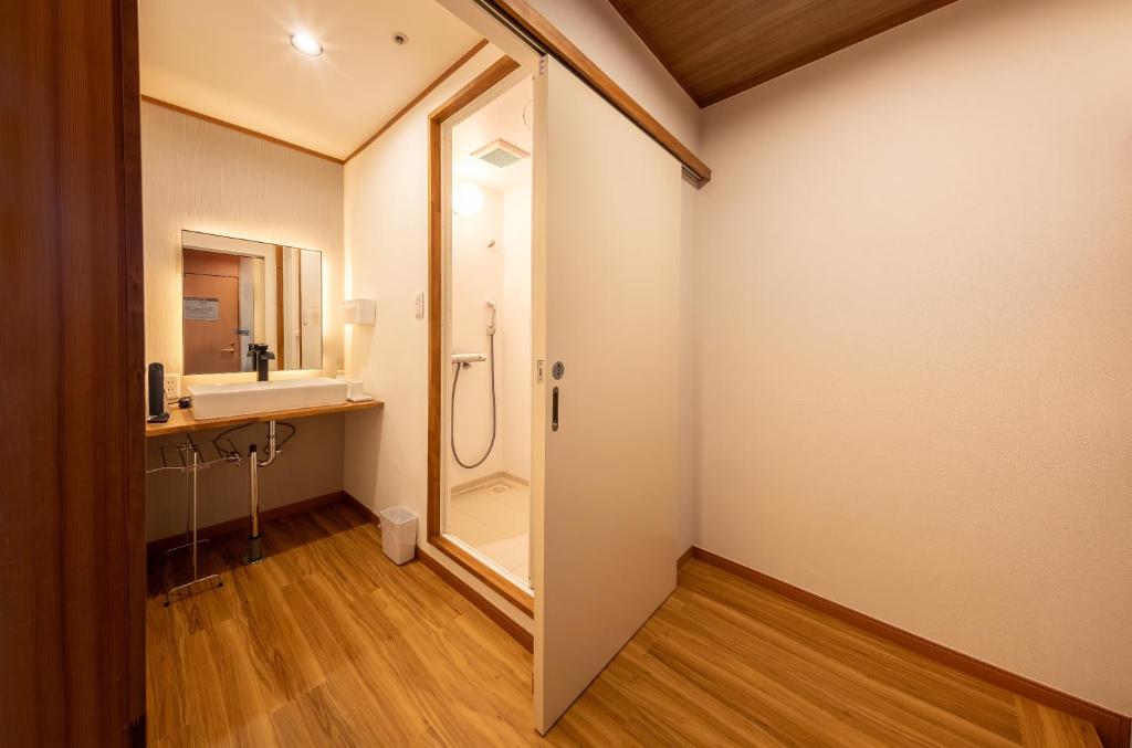une salle de bain avec douche et lavabo dans l'établissement Enakyo Onsen Hotel Yuzuriha, à Ena