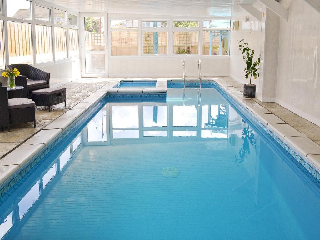ein Swimmingpool mit blauem Wasser in einem Gebäude in der Unterkunft The Pool House in Tywardreath