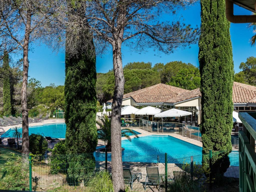 サン・ラファエルにあるGarrigae Domaine de l'Esterelの木々が植わるリゾートのプールの景色を望めます。