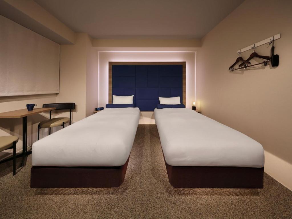 two beds in a small room with a table and a bed sidx sidx at Dotonbori Crystal Hotel - Vacation STAY 77468v in Osaka