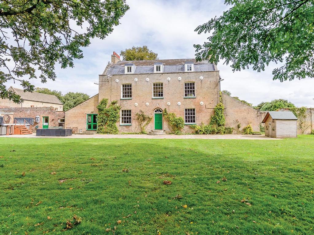 an old stone house with a green lawn at Lode Hall in Upwell