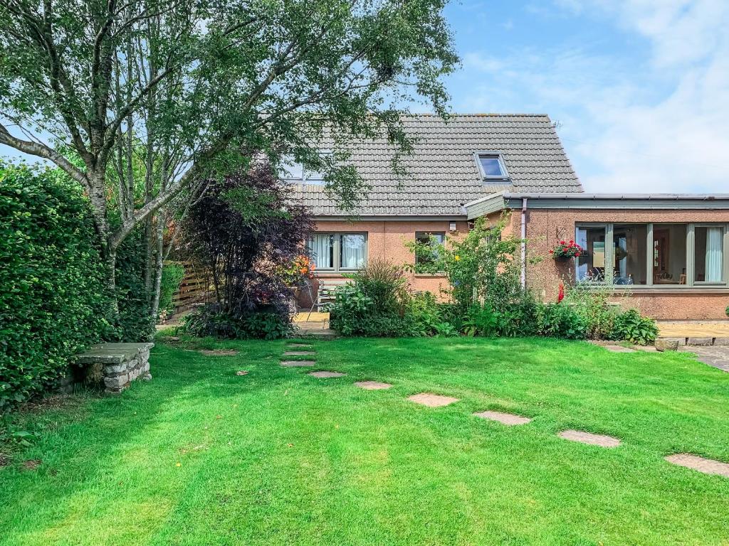 a house with a green yard in front of it at Sheildaig Cottage Annex in Laurencekirk