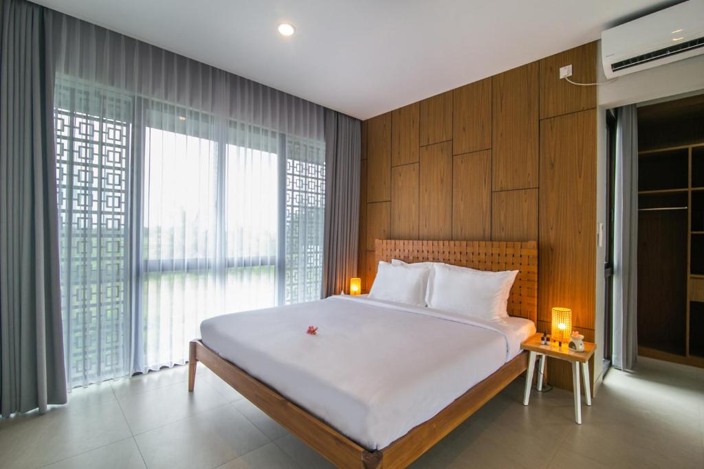 a bedroom with a large white bed and a large window at Nusa Djiwa in Tanah Lot