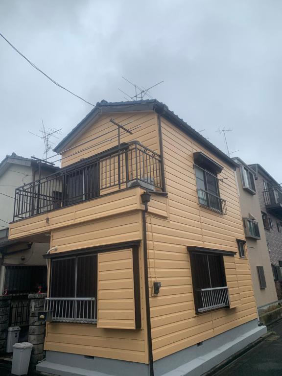 ein Holzgebäude mit einem seitlichen Balkon in der Unterkunft 仁信小屋 in Tokio