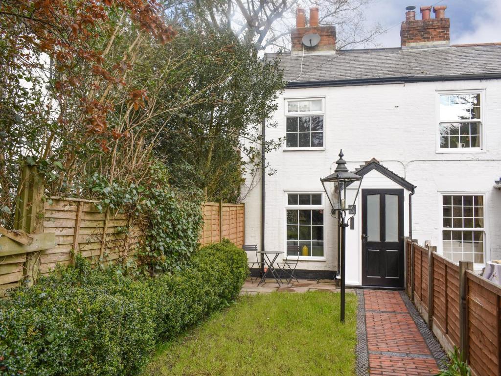 a white house with a black door and a fence at Lantern Cottage in Lyndhurst