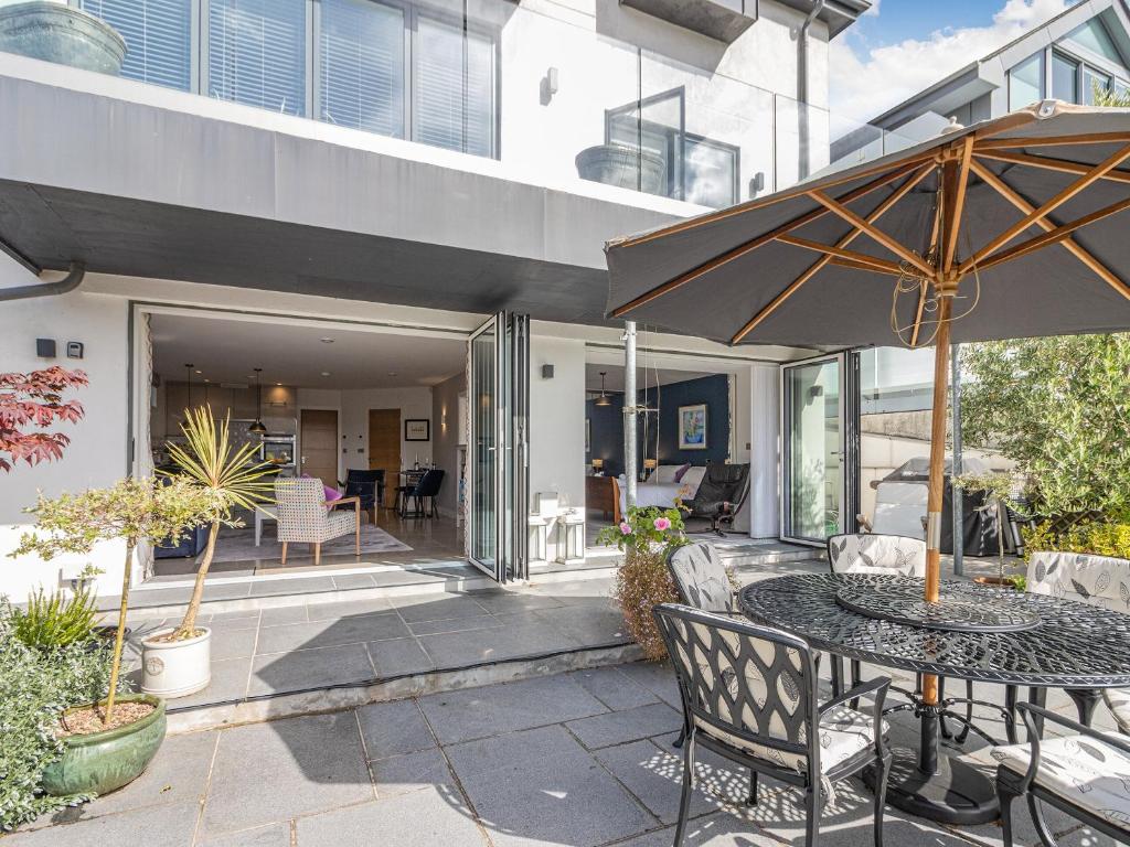 un patio con una mesa y una sombrilla en River Coombe, en Dartmouth