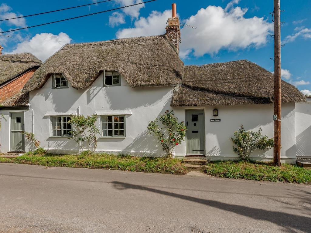 a white house with a thatched roof at Eton Cottage in Farnham