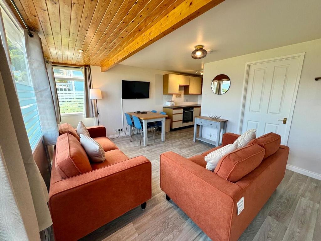 ein Wohnzimmer mit 2 Sofas und einer Küche in der Unterkunft Beach Cottage 6 - Bright & Modern By the Sea in Westward Ho