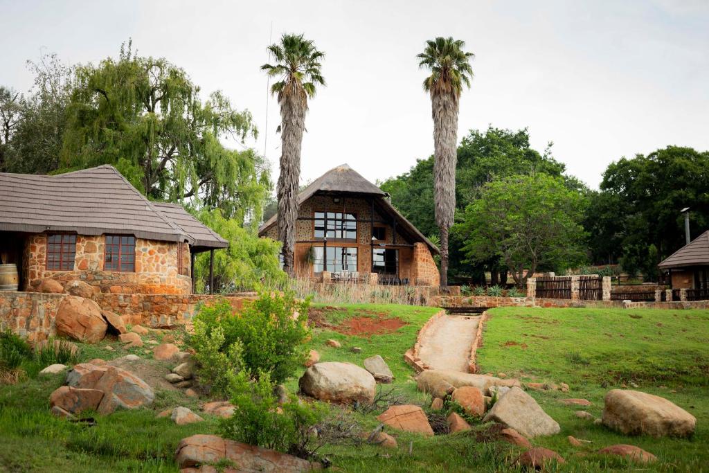 a house with palm trees in front of a yard at Riverman Cabin Country Lodge - Tonteldoos in Tonteldoos