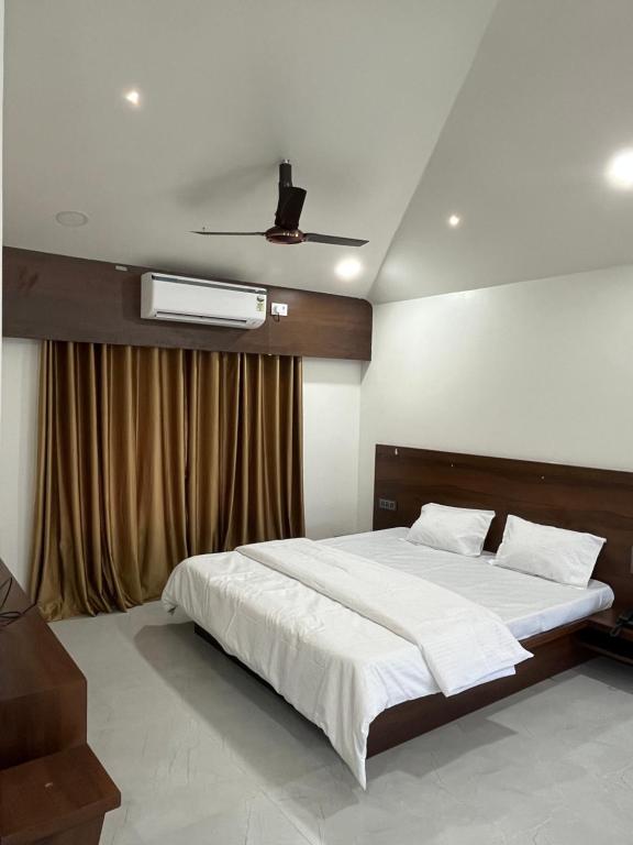 Un dormitorio con una cama y un ventilador de techo. en The Glen Yard Farms, en Tumsar