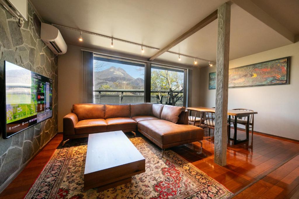 un salon avec un canapé en cuir et une télévision dans l'établissement Yufuin Kaze no Mori, à Yufu