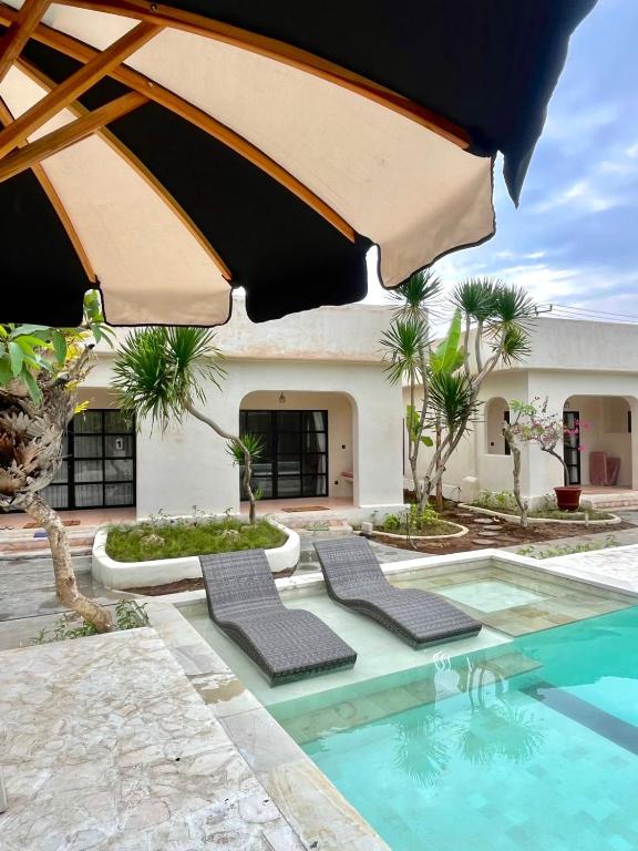 a pool with two chairs and an umbrella at El Campo Mushroom in Nusa Lembongan