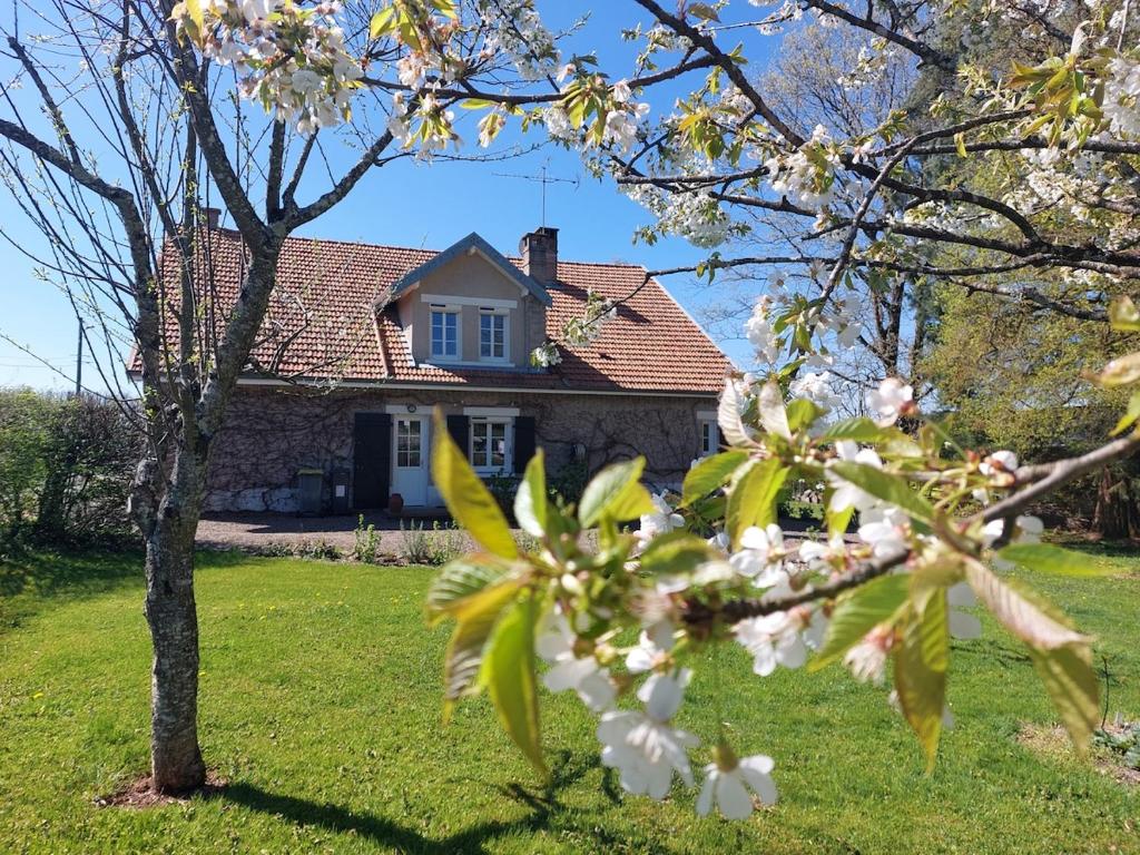 una casa con un albero da fiore di fronte di Un Détour Par Thiénans cottage entier 