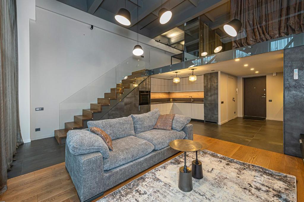 un salon avec un canapé et un escalier dans l'établissement Parko namai-loftas, à Kaunas