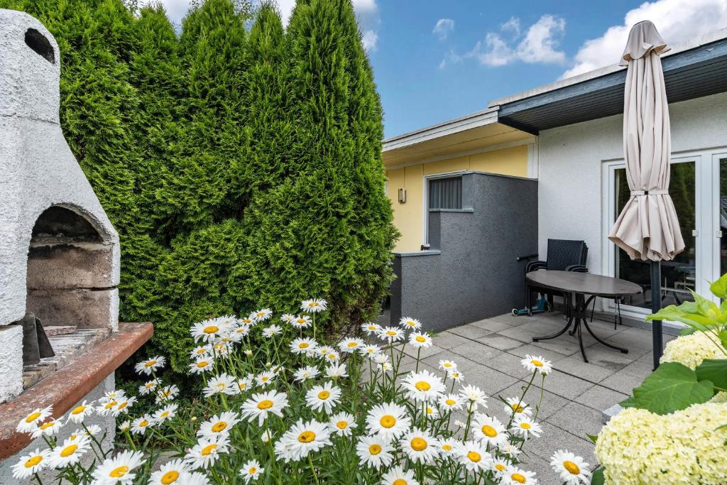 a patio with flowers and a table and an umbrella at Bungalow 73 in Zadelsdorf