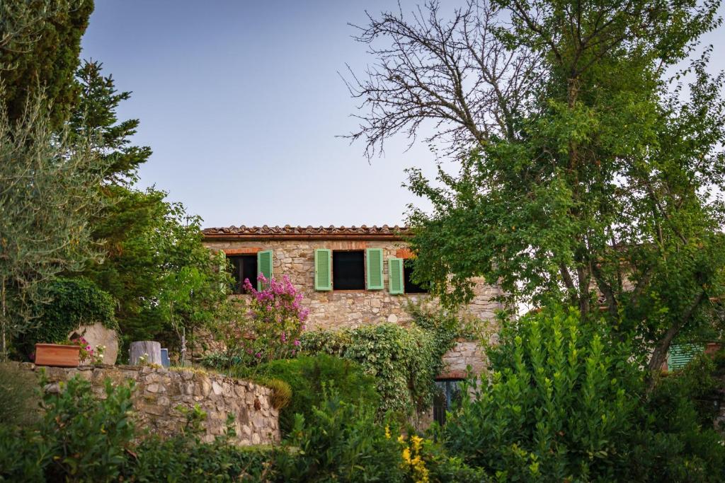 a stone house with green shutters in a garden at Celle di Lecchi Vigneto in San Sano