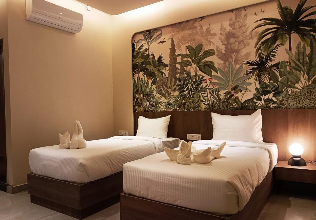 2 Betten in einem Hotelzimmer mit Wandbild in der Unterkunft Hotel Muthahalli Grand in Bangalore