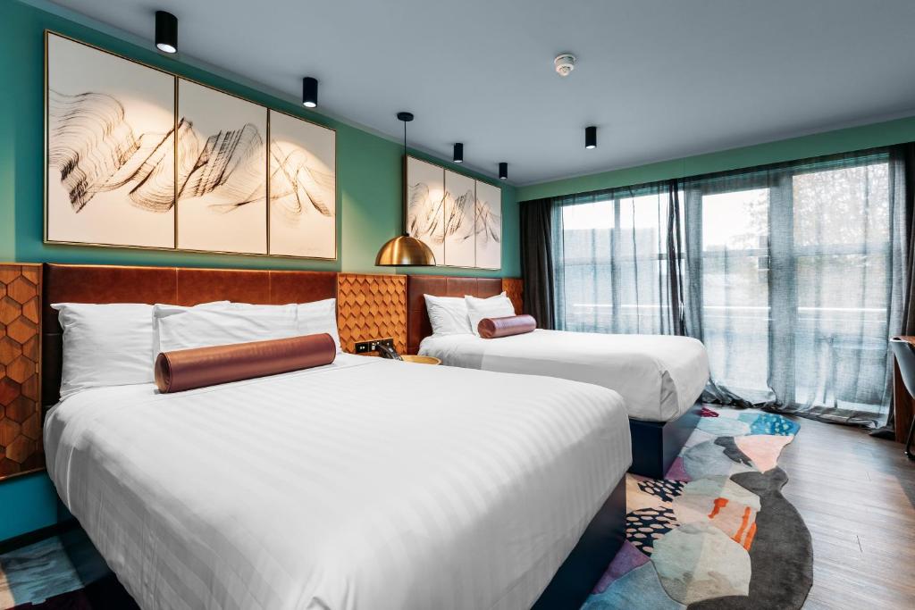 two beds in a room with green walls and windows at Naumi Auckland Airport Hotel in Auckland