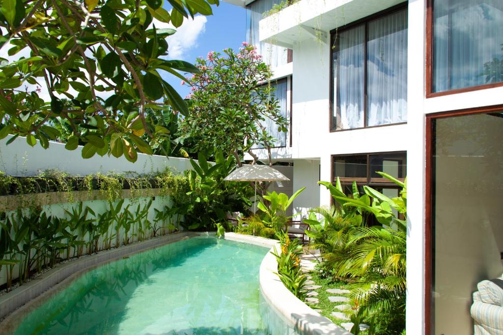 a swimming pool in a garden next to a building at Ducat Living in Canggu