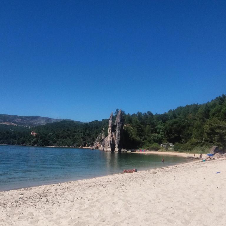 a beach with a large rock in the water at Ha Mar ao Luar in Setúbal