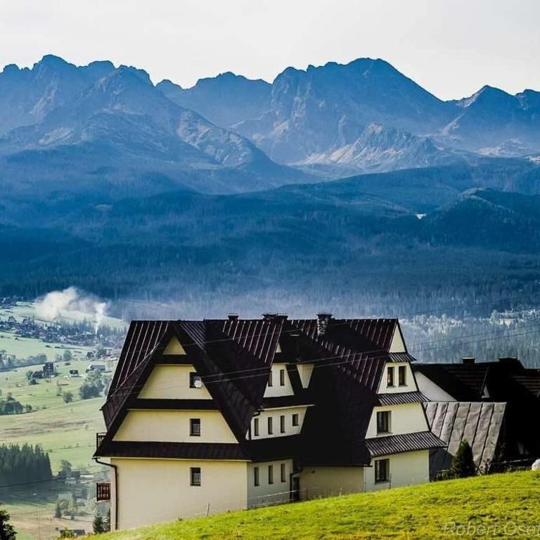 a house on a hill with mountains in the background at Pokoje Gościnne Stołowe in Gliczarów Górny