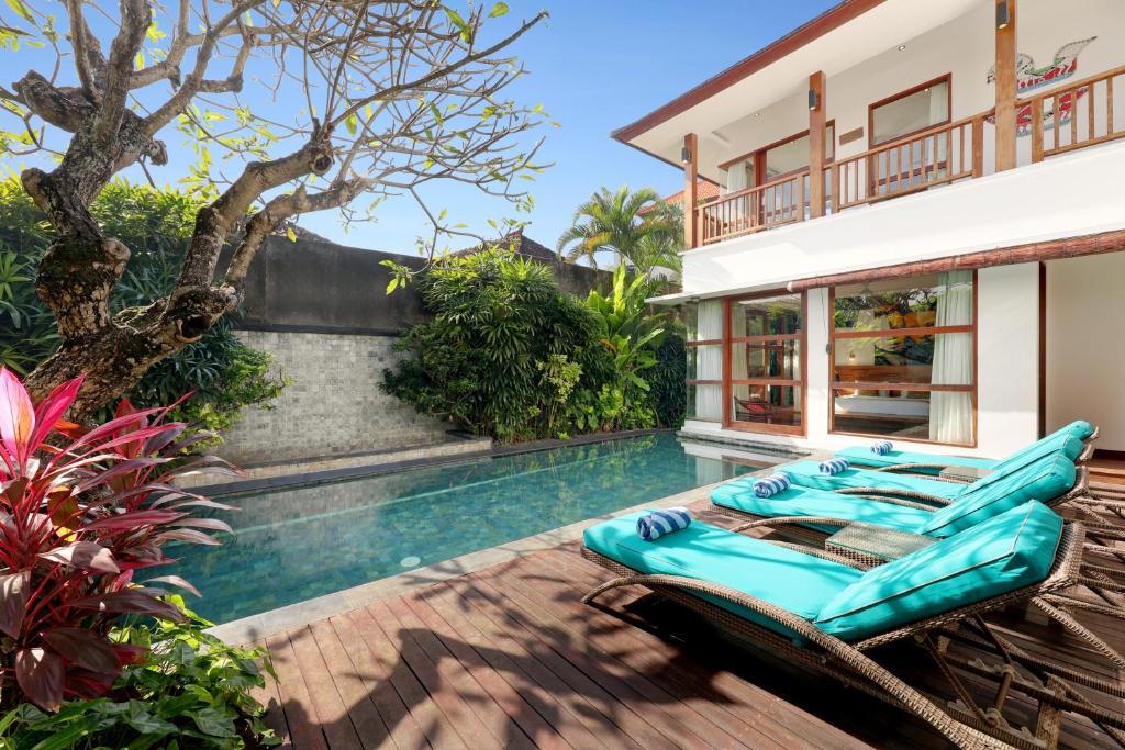 una piscina con tumbonas junto a una casa en Villa Amira Legian, en Legian