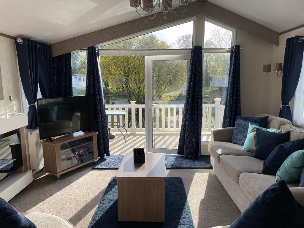 a living room with a couch and a tv at Stunning 2 Bed Caravan on the Lake Front in Gloucestershire