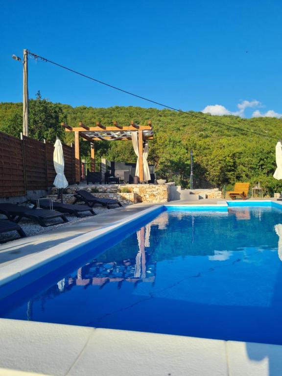 a swimming pool with a pergola and blue water at Kamena kuća Goranci in Mostar